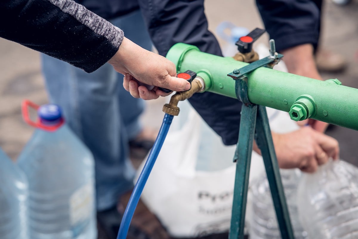 Ukrainians collect water at a tap stand