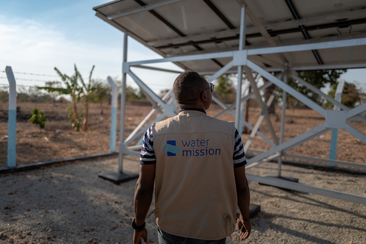A Water Mission engineer looks at solar panels