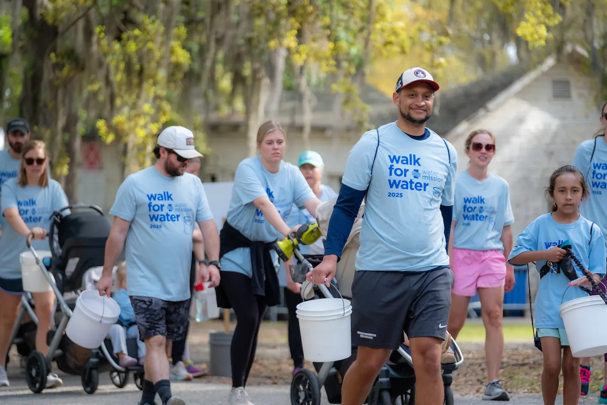 Walkers smile while carrying buckets