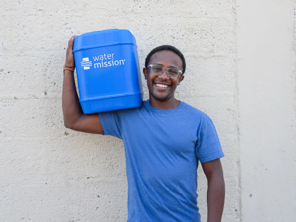A Water Mission Champion carries a jerrycan
