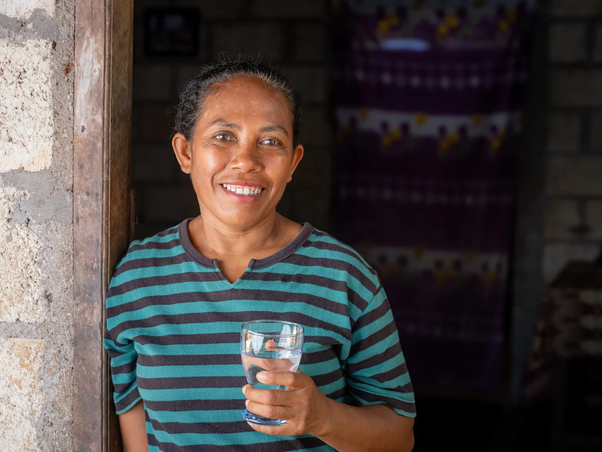 Martha holds a glass of safe water in Bonenea, Indonesia