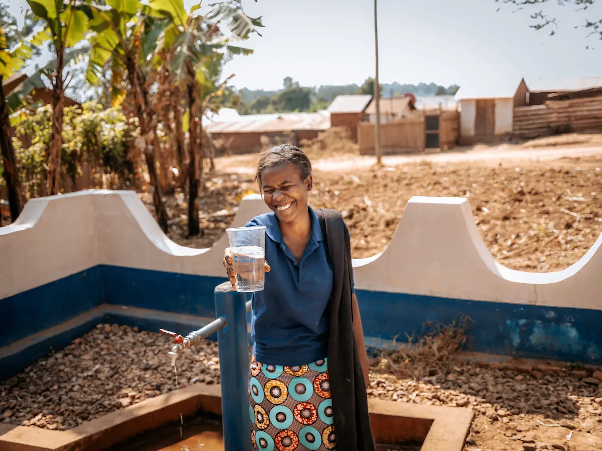 Jackline smiling with cup of safe water