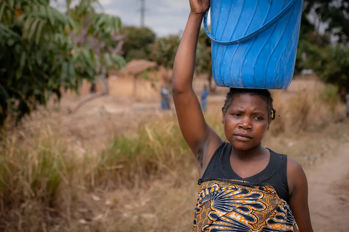 African woman carries bucket of water on her head