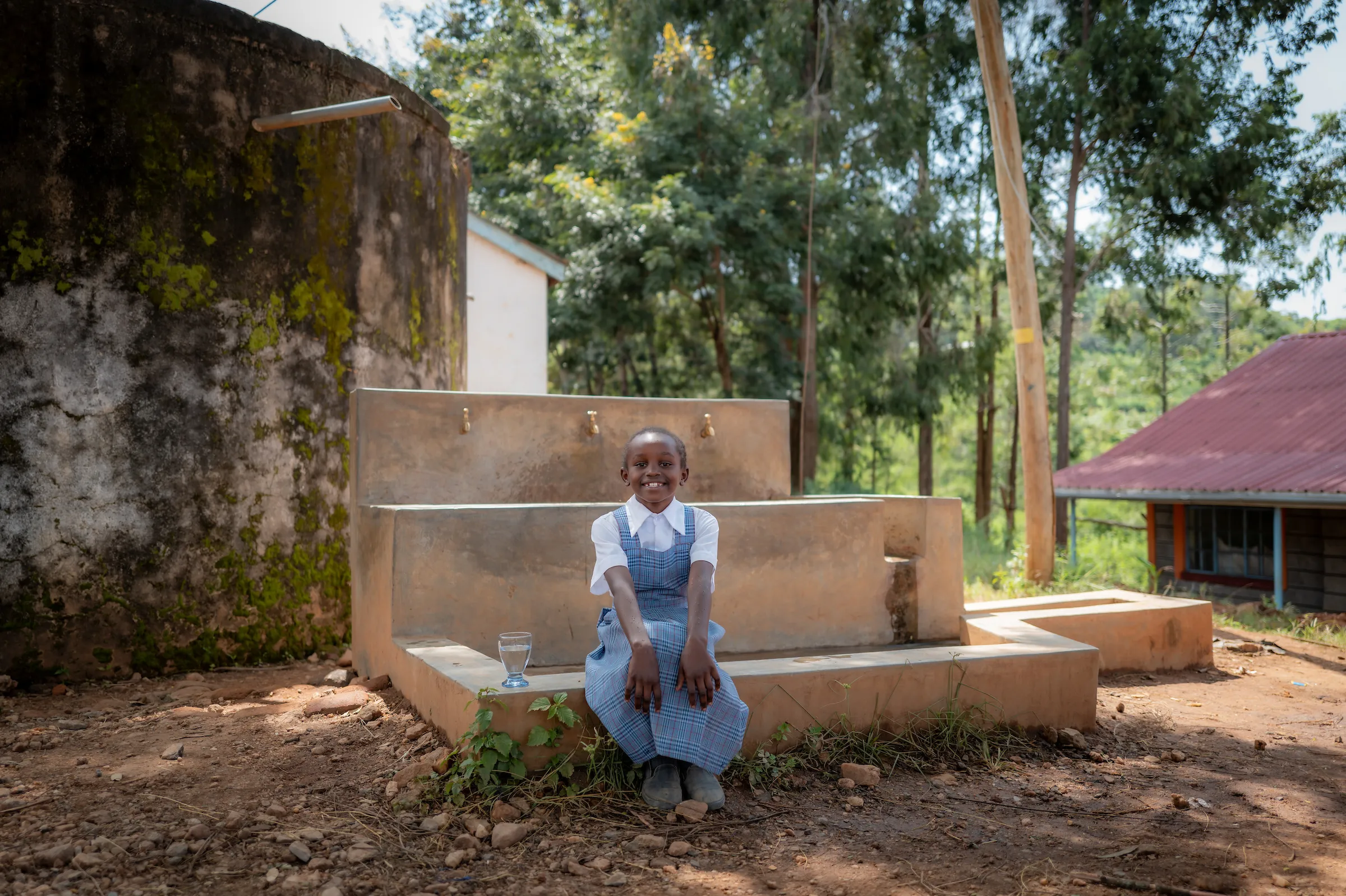 A young girl sets in front of a tap stand in Mutulani, Kenya