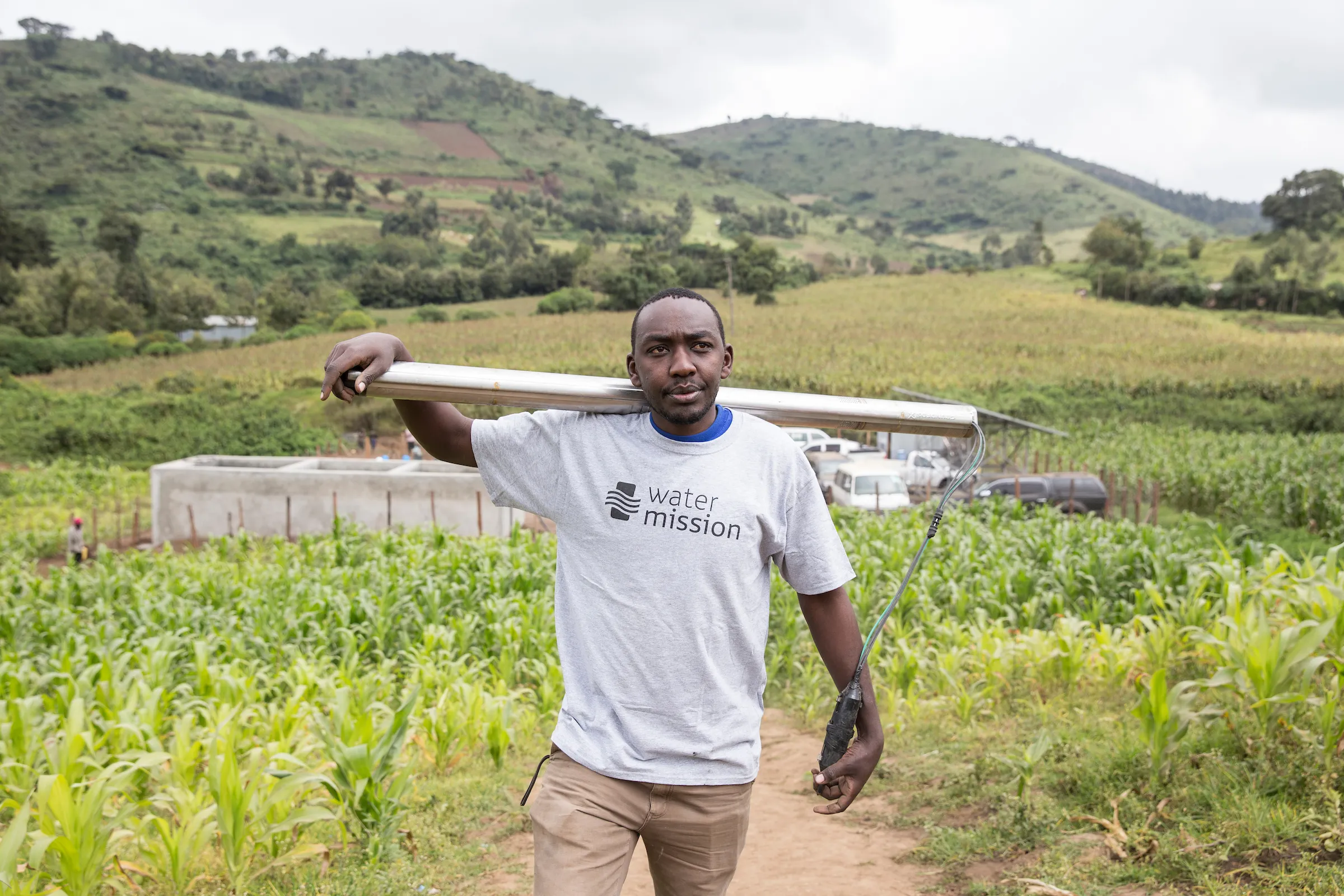 A Water Mission team member carries a surface pump in Enariboo, Kenya