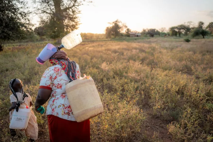 With large jerrycans on their backs, Celestine and Grandma Anne make the long trek to the Kambu River to collect water for drinking, washing, and bathing.