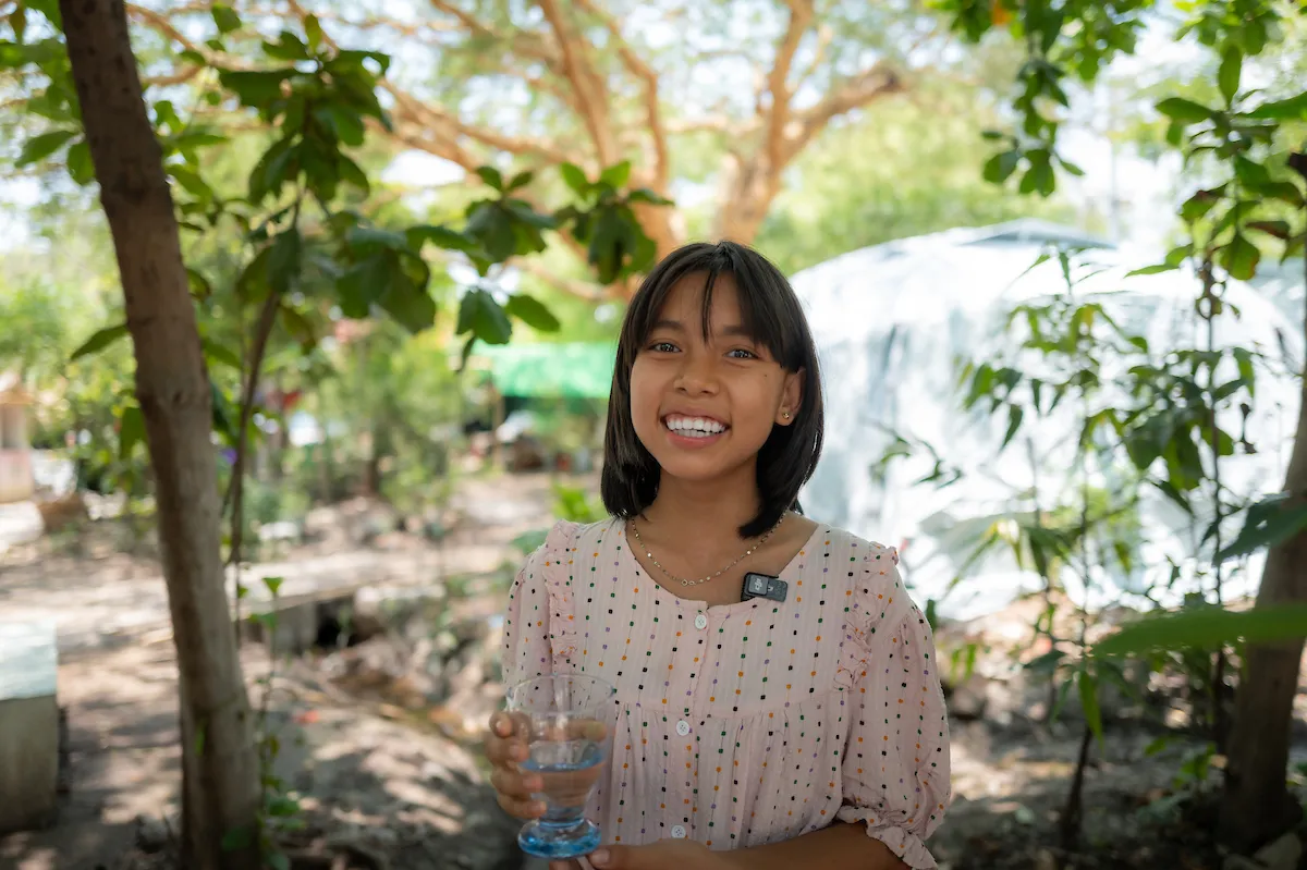 Young girl holds cup of water and smiles