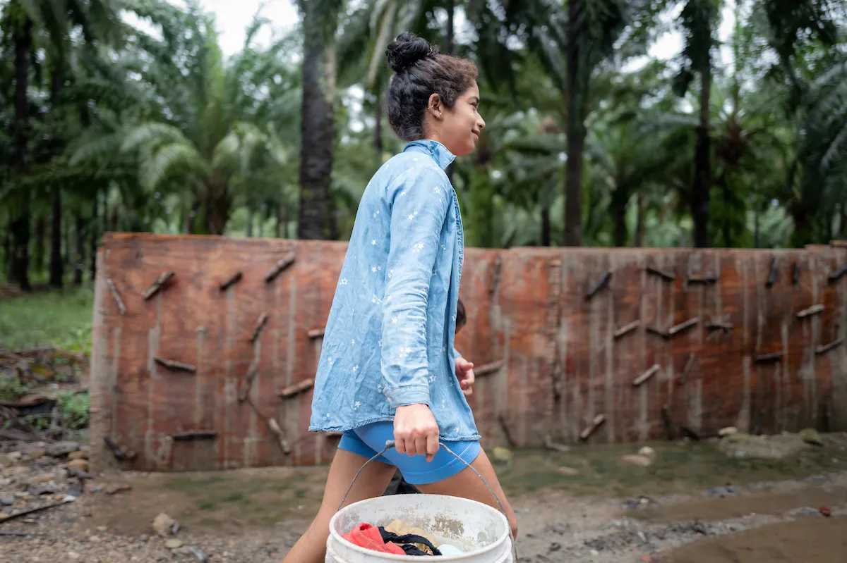 Rosa walks with water bucket
