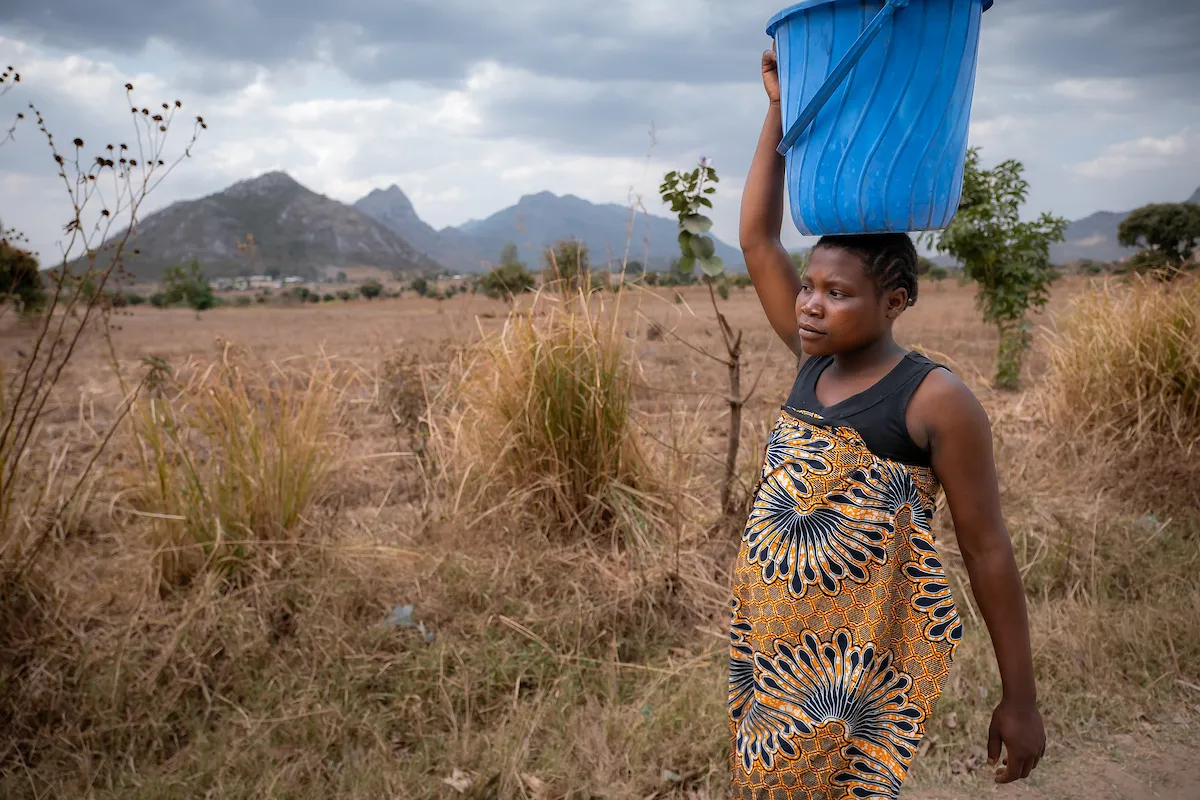 African woman carries bucket of water on her head