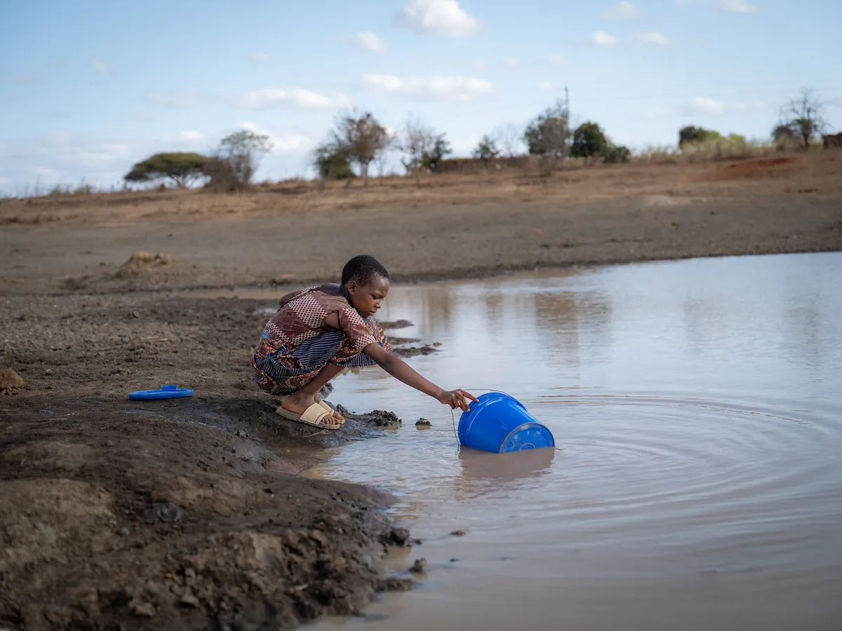 A young girl in Tanzania gathers dirty water