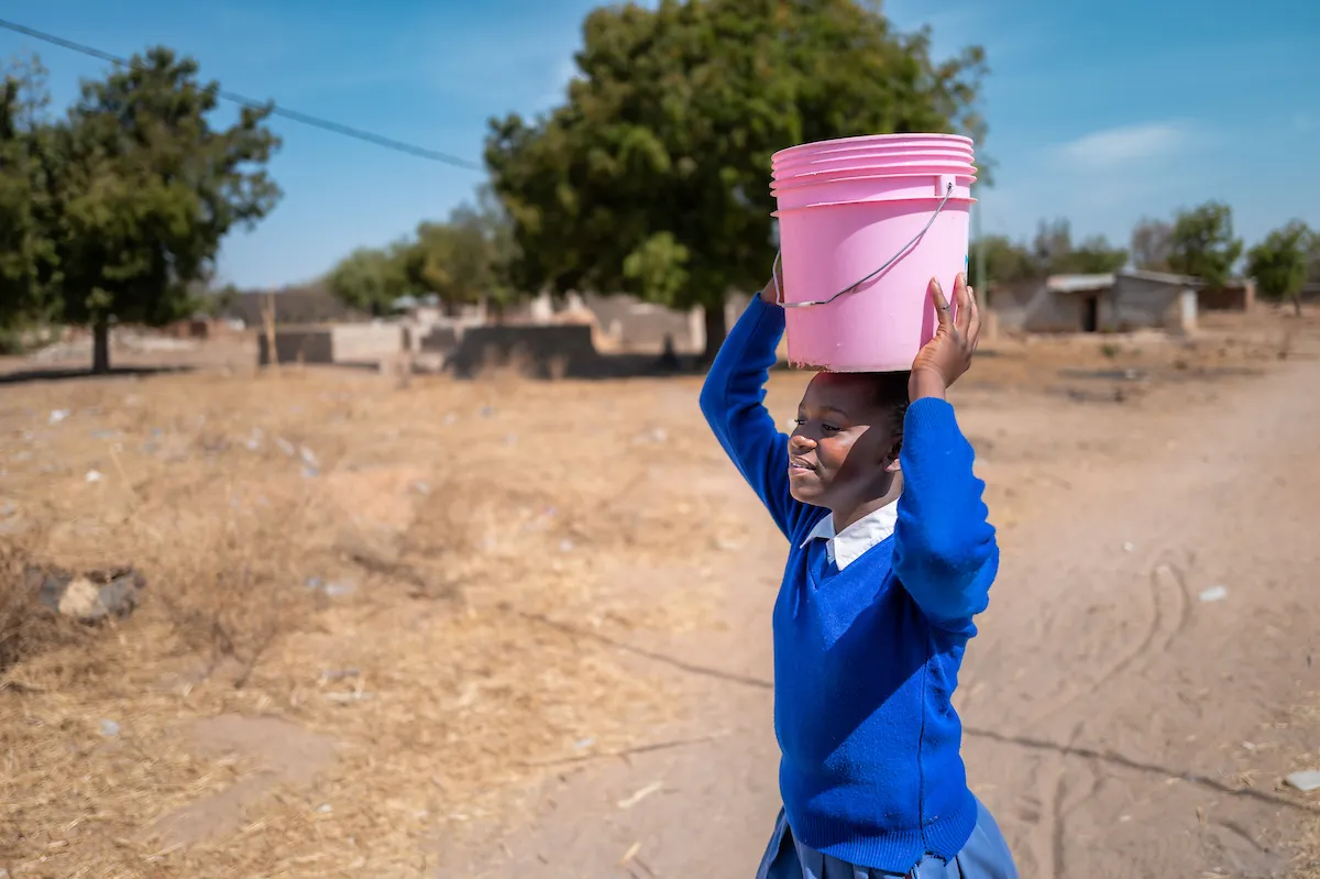Girl carries pink bucket over her head