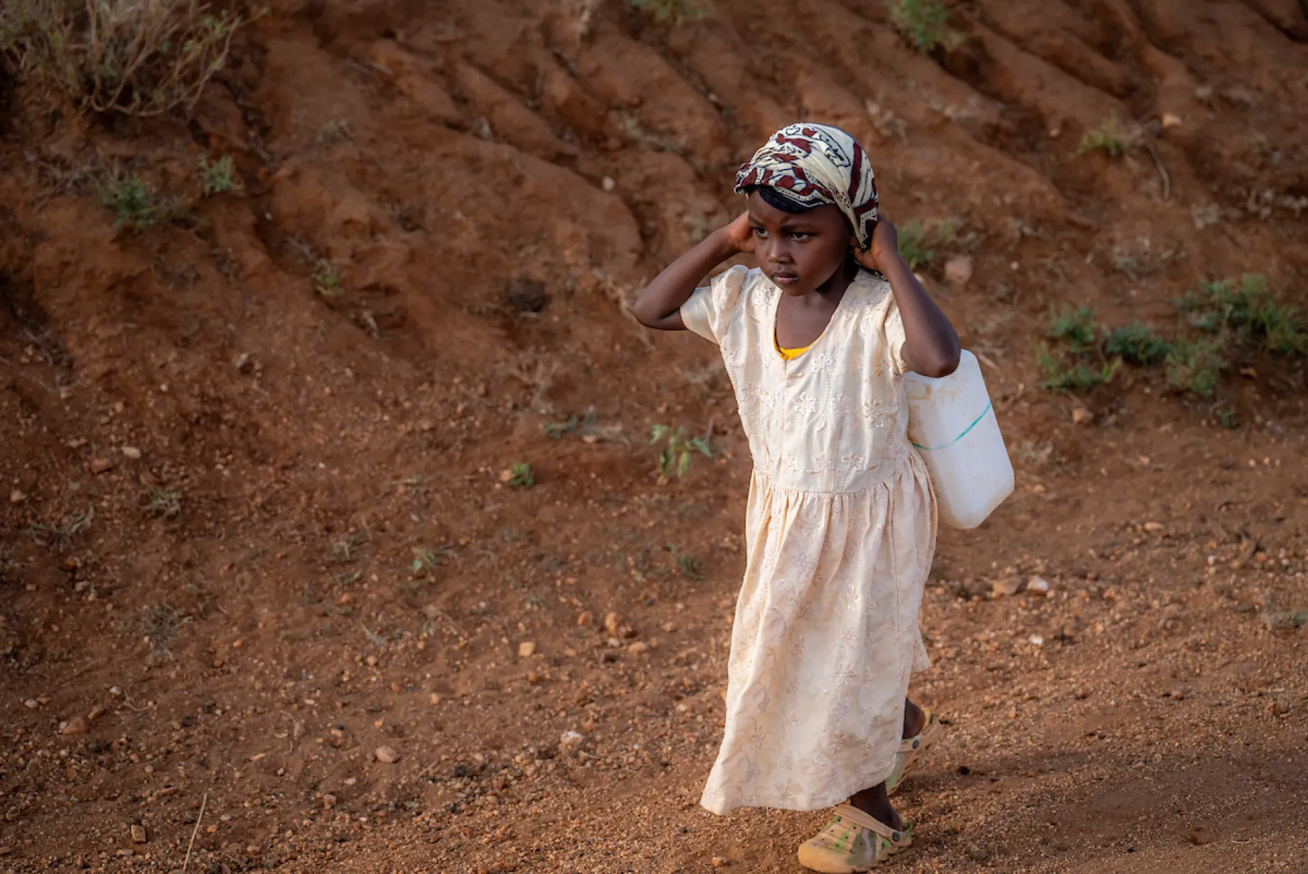 A young girl walks for water carrying bucket
