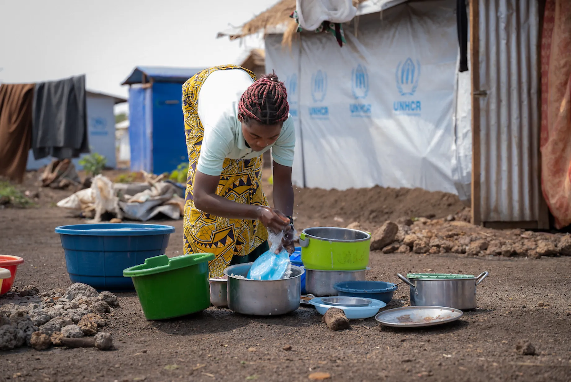 Katembo washes dishes; Nyarugusu refugee camp; Tanzania, Africa