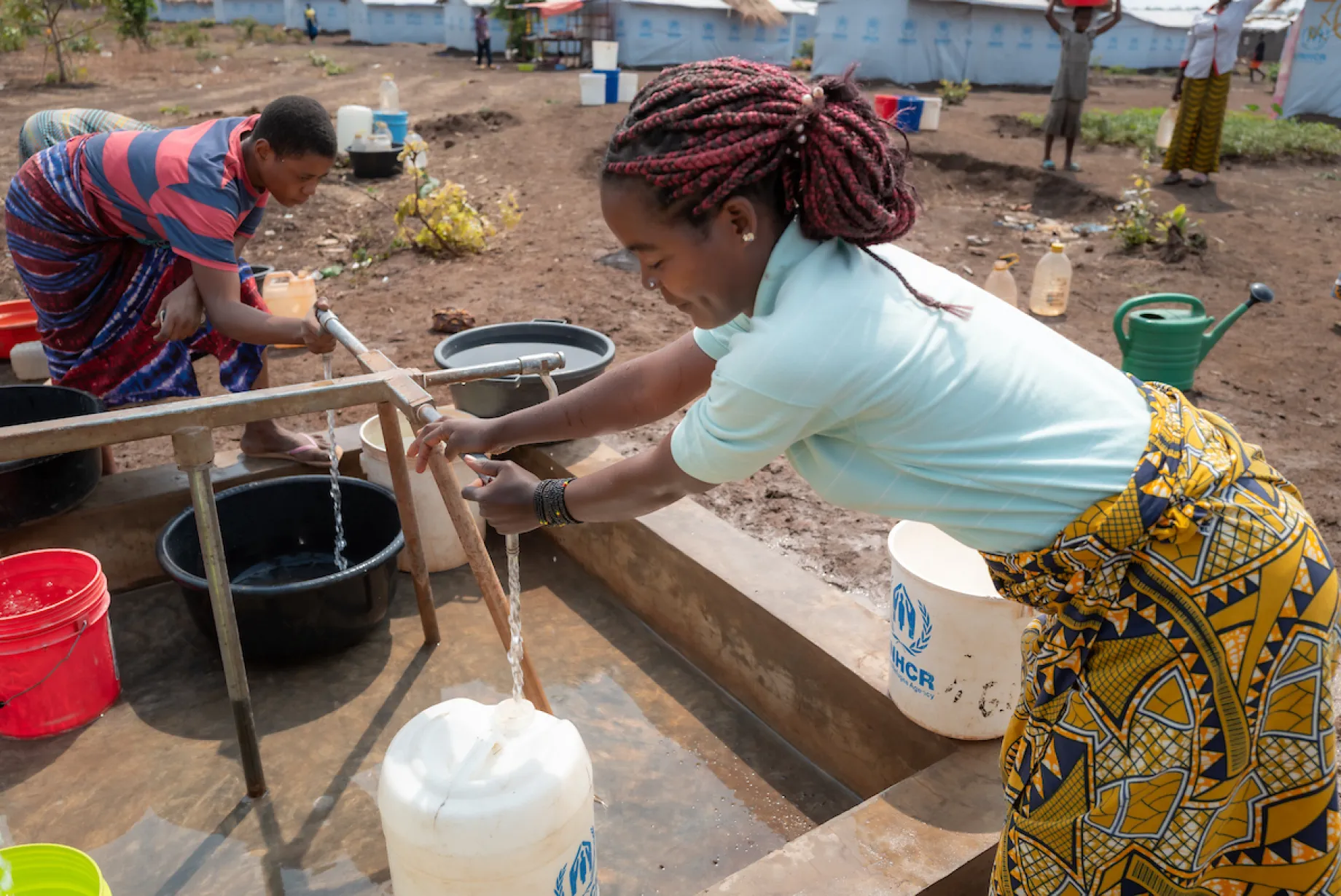 Katembo accesses safe water via tapstand; Nyarugusu refugee camp; Tanzania, Africa
