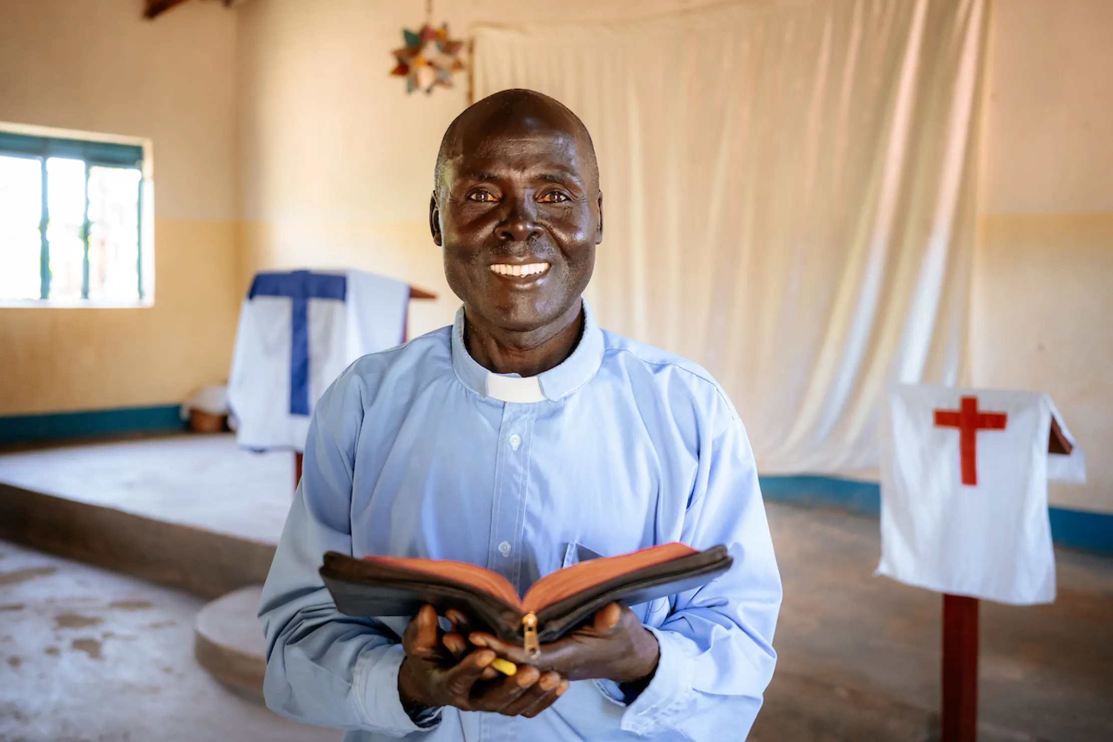 Pastor Laston smiling and holding open Bible