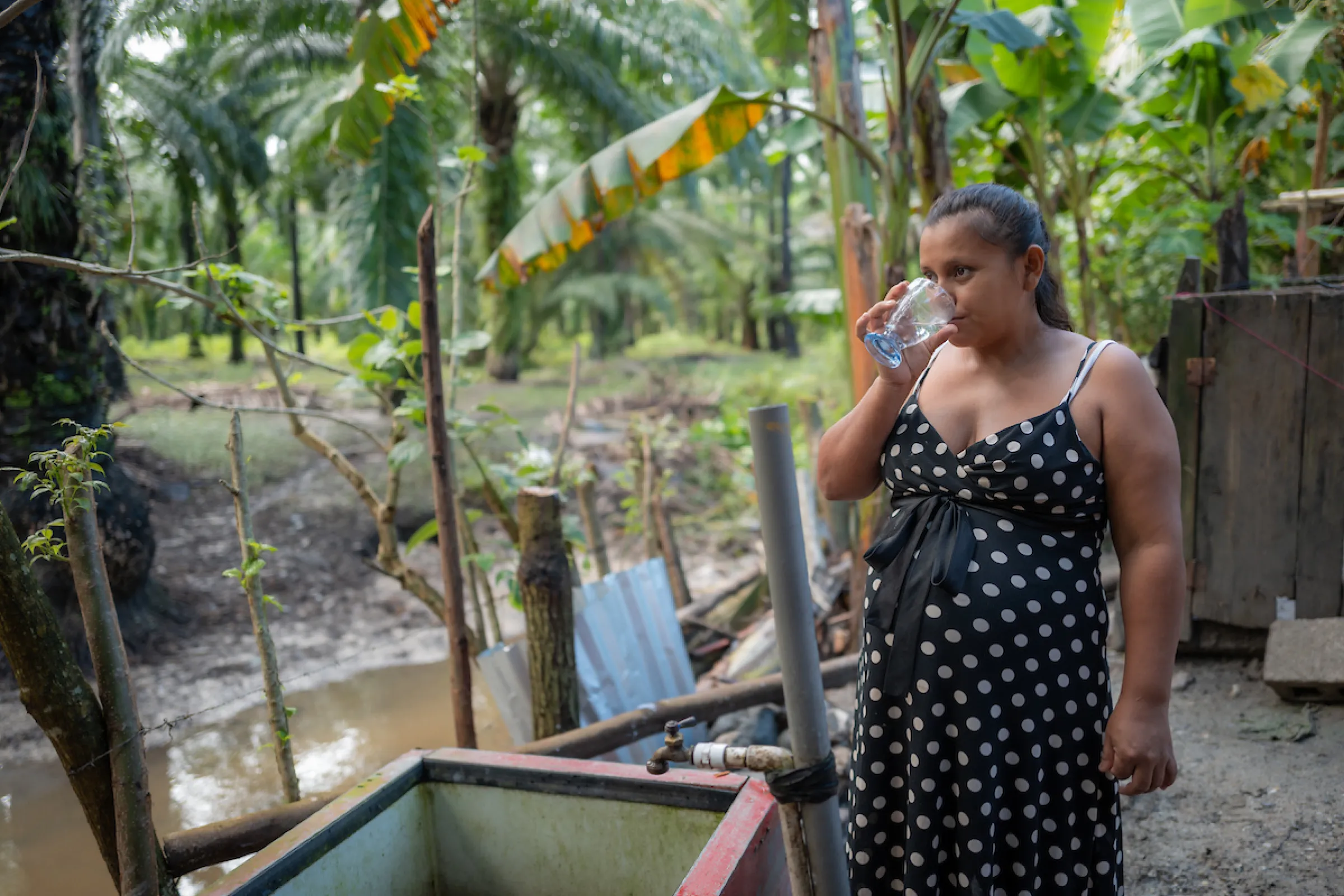 Woman stands by dirty water