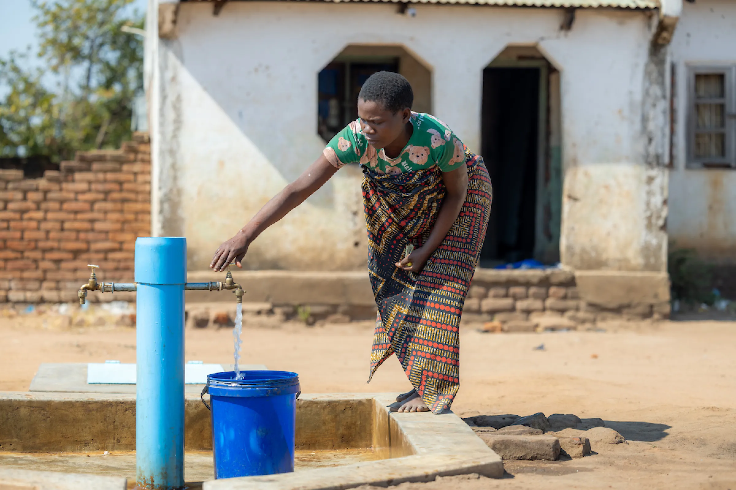 A woman draws water from a Water Mission tapstand