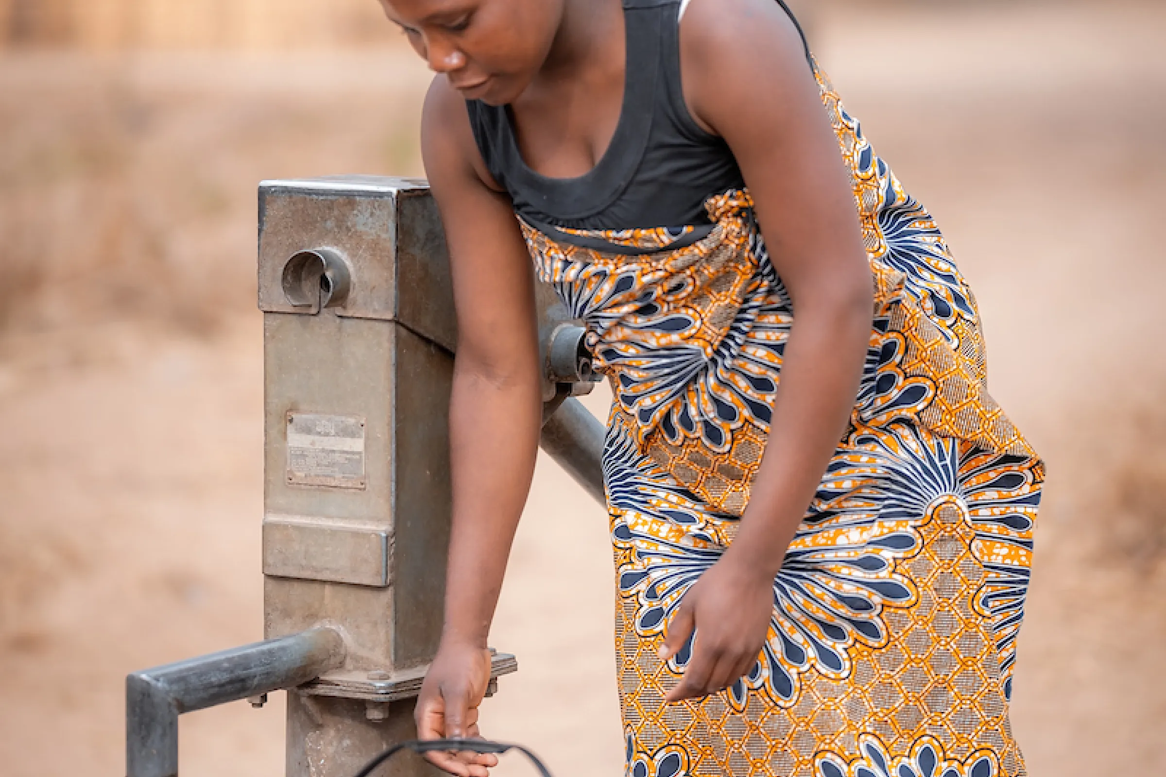 African woman fills bucket with water