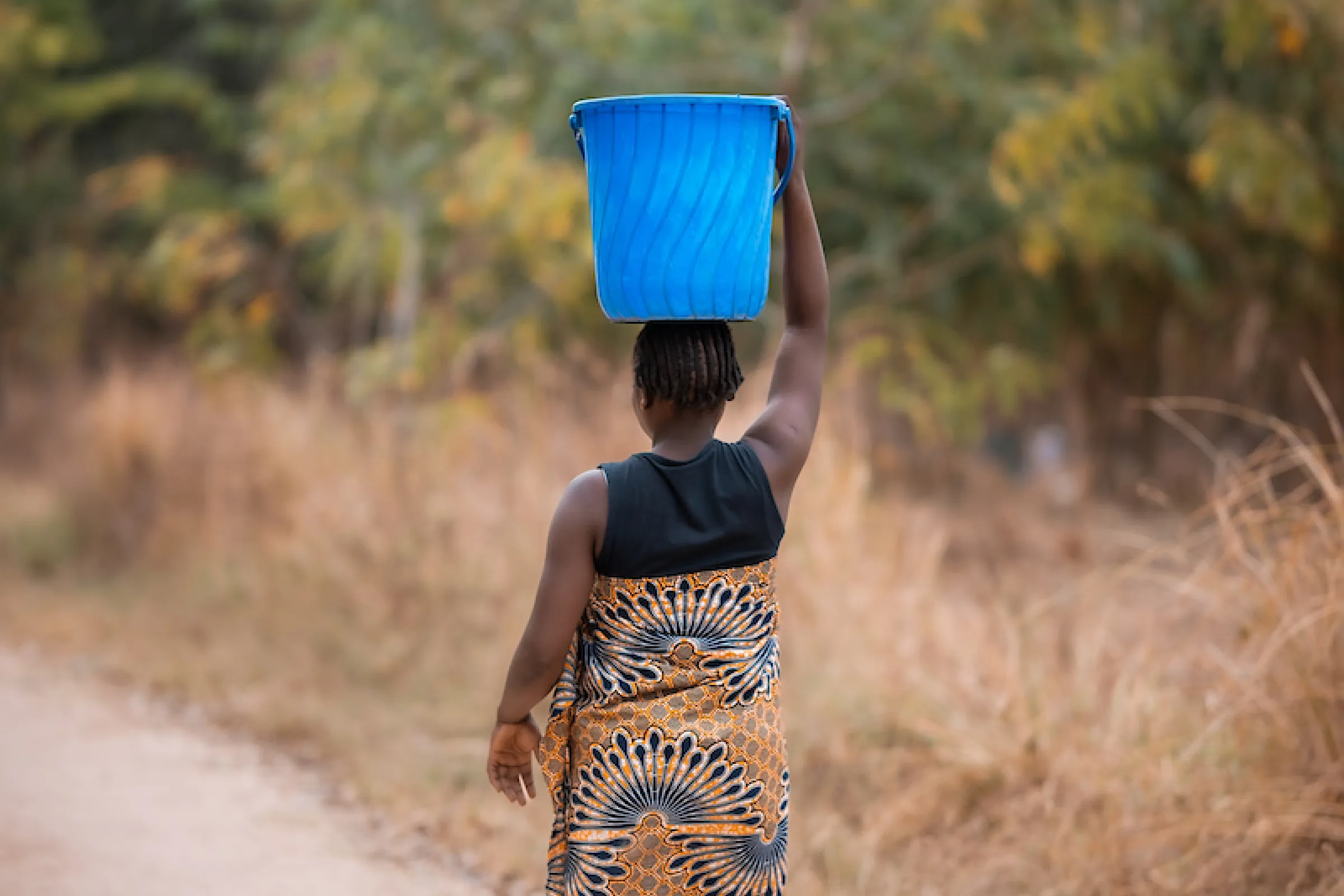 African woman carries bucket on her head