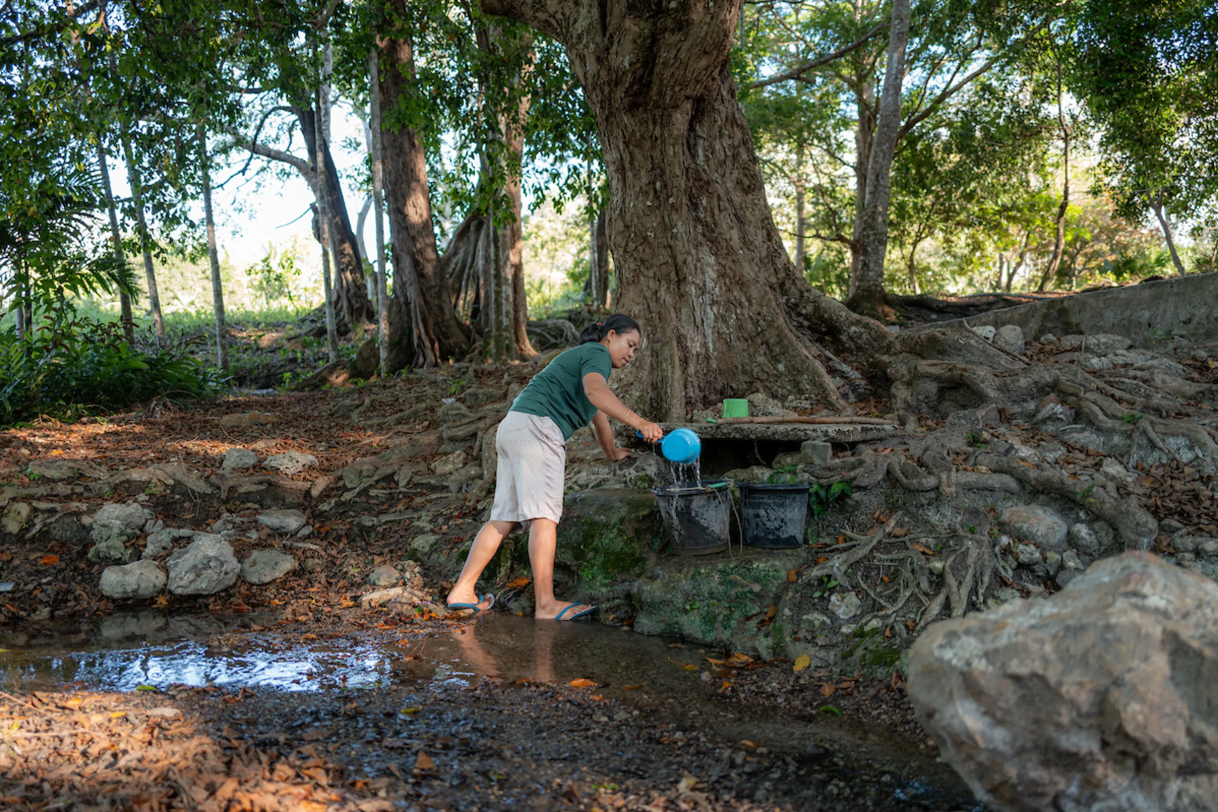 Delti washes clothes in a stream in rural Indonesia