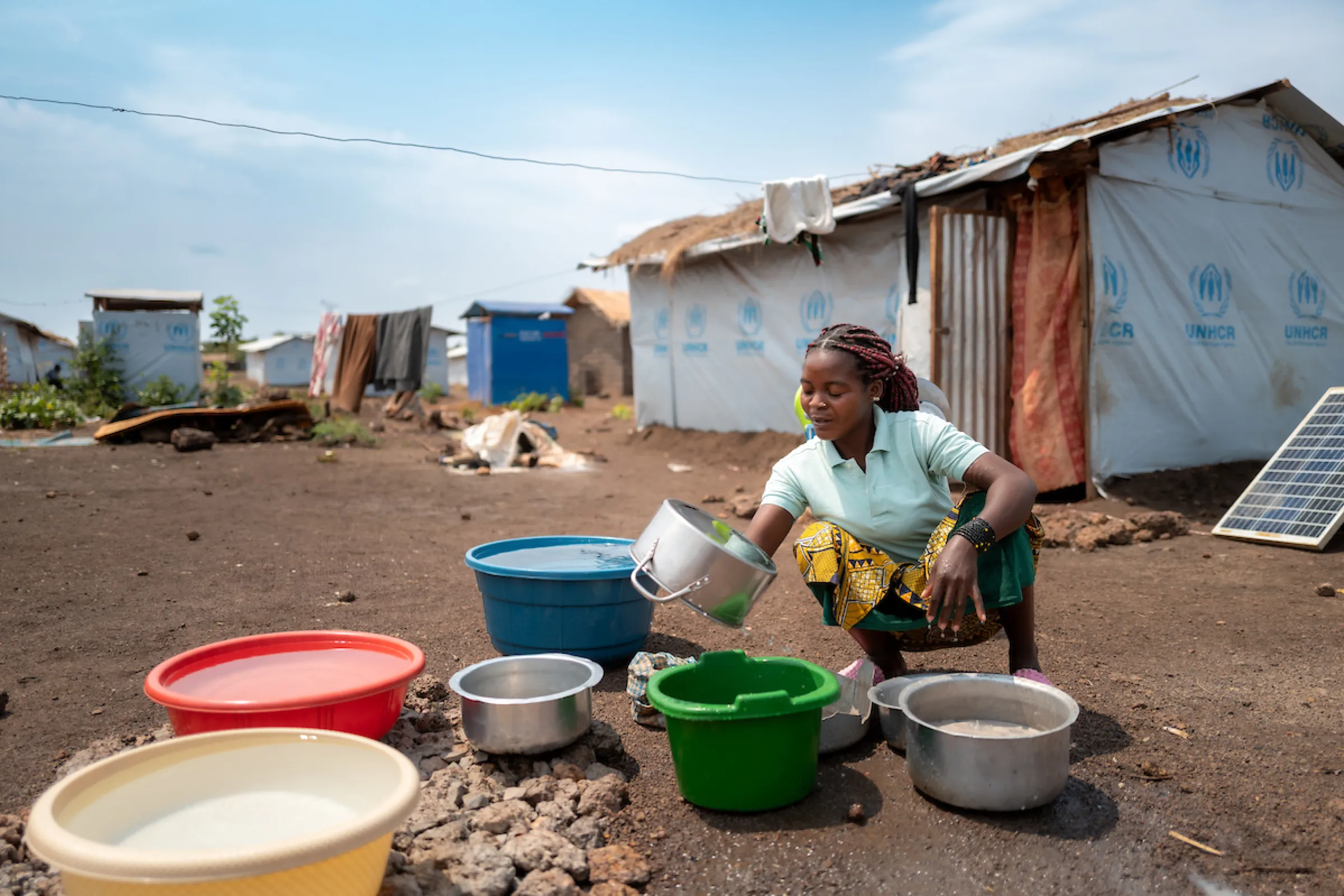 Katembo washes dishes; Nyarugusu Refugee Camp; Tanzania, Africa