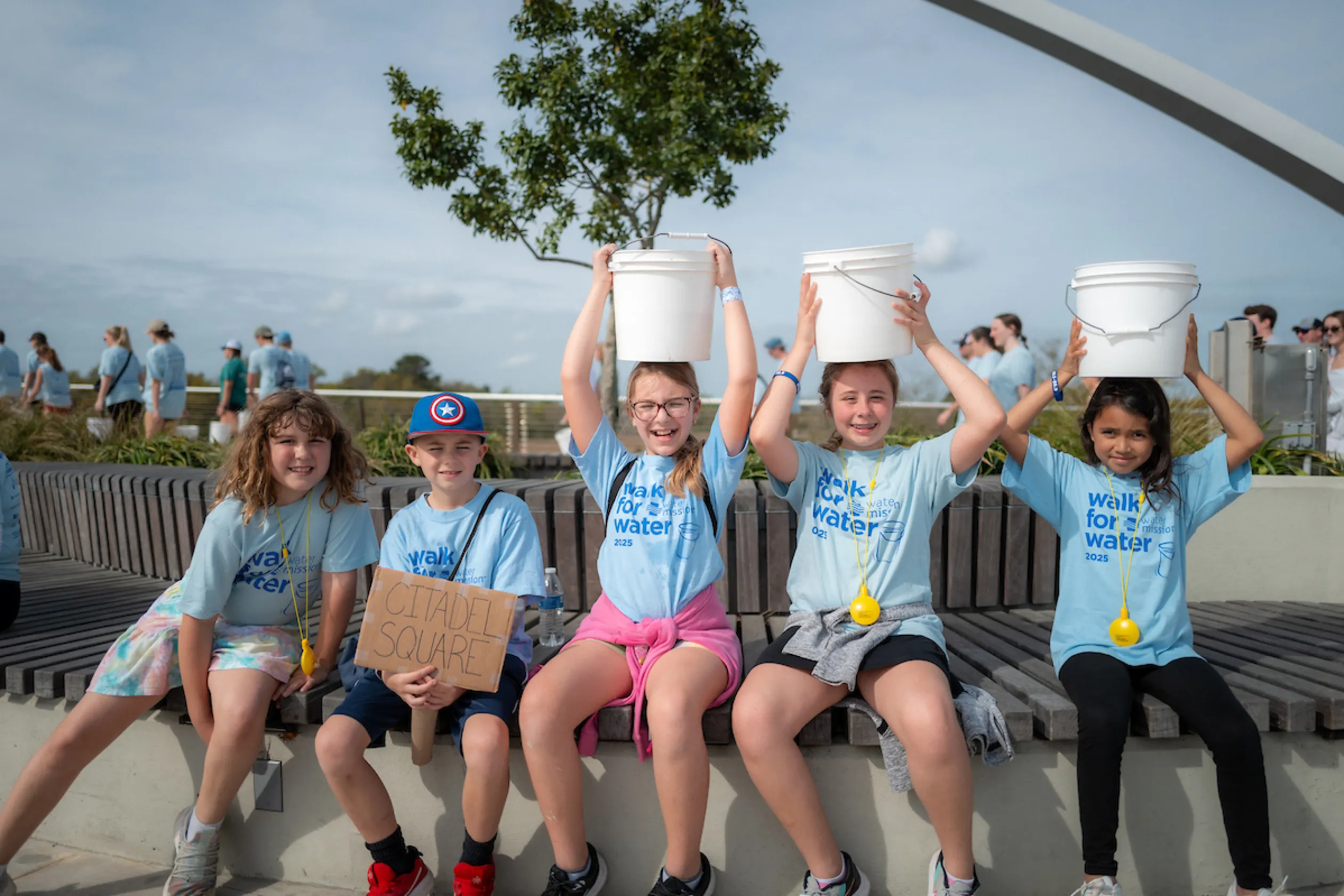 Young walkers hold buckets on their heads