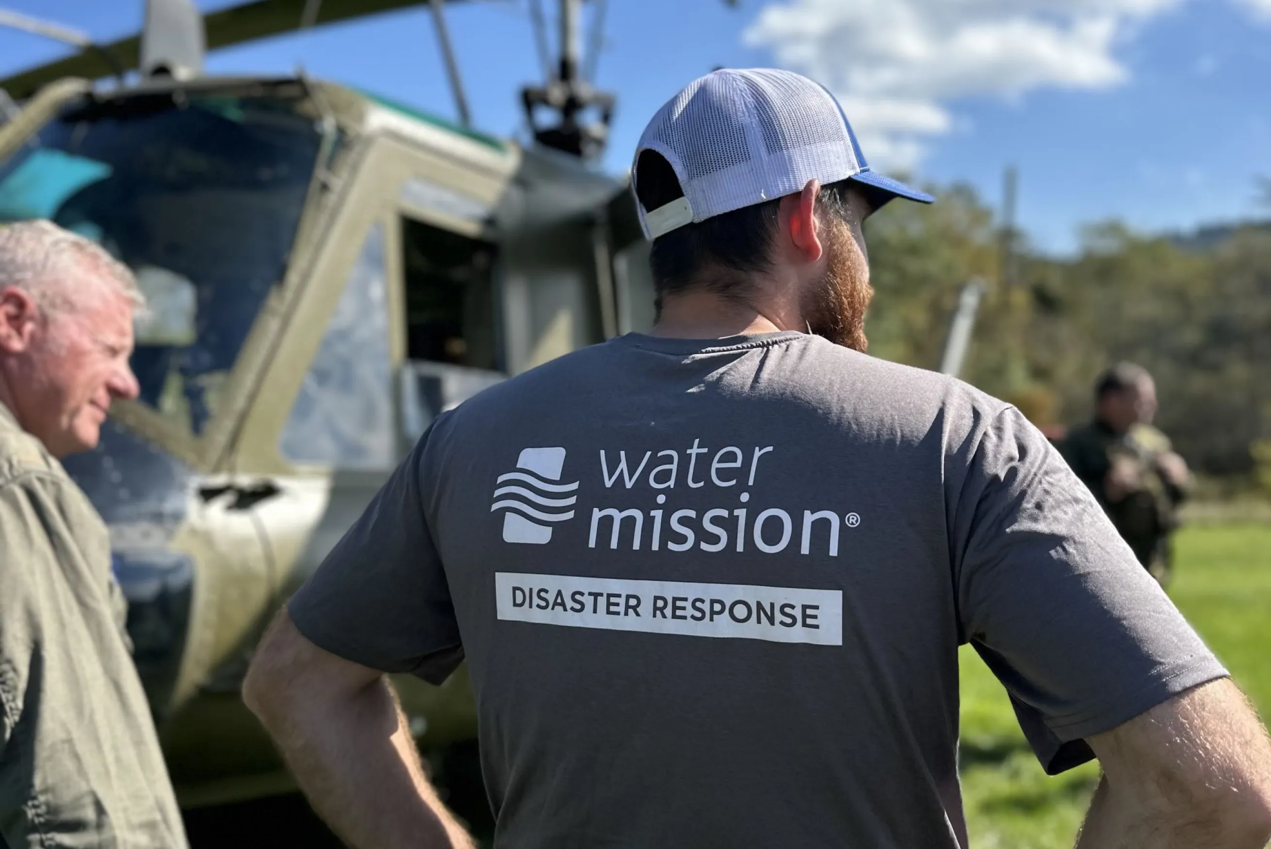 Water Mission staff members receive emergency supplies via helicopter