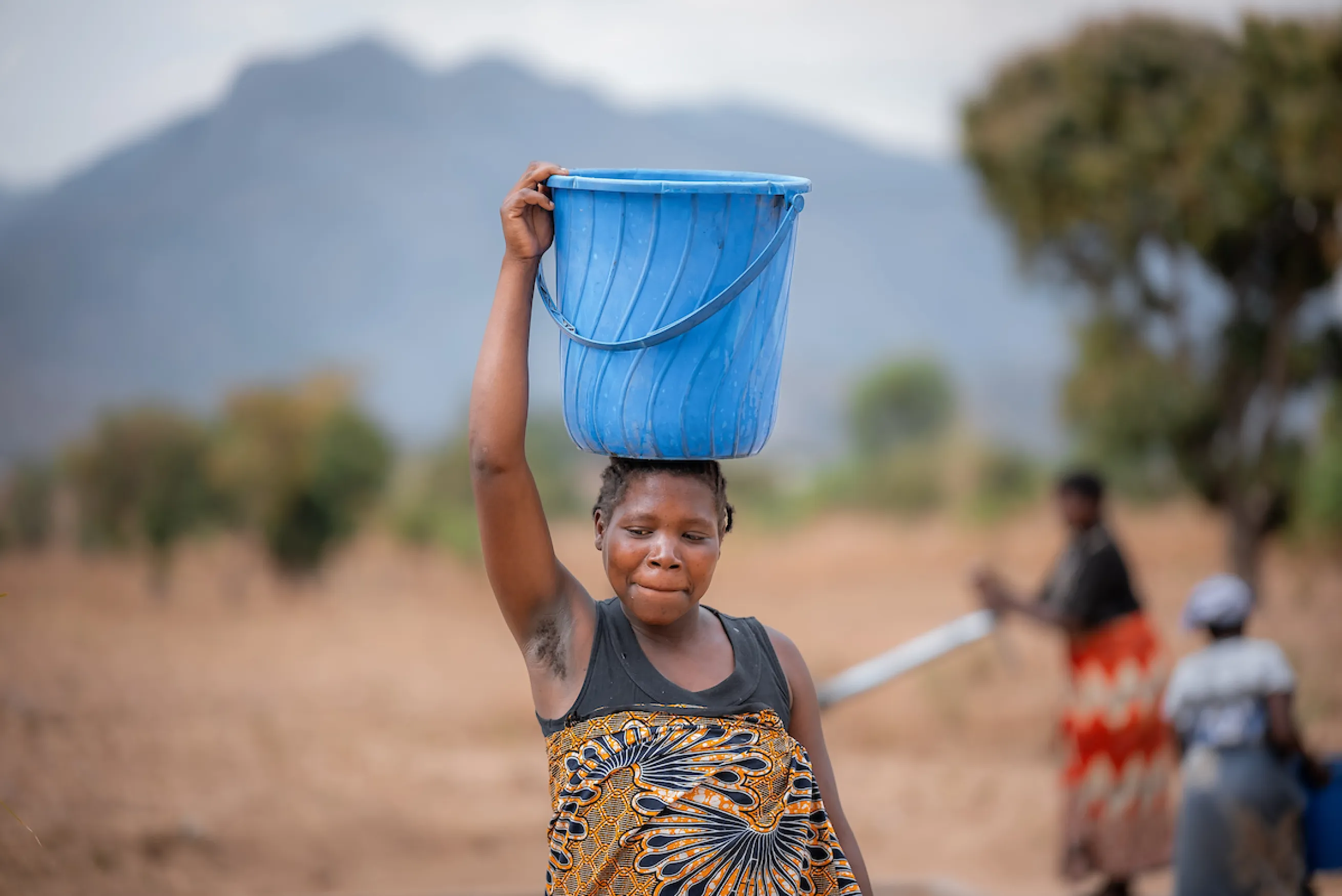 African woman carries bucket of water on her head