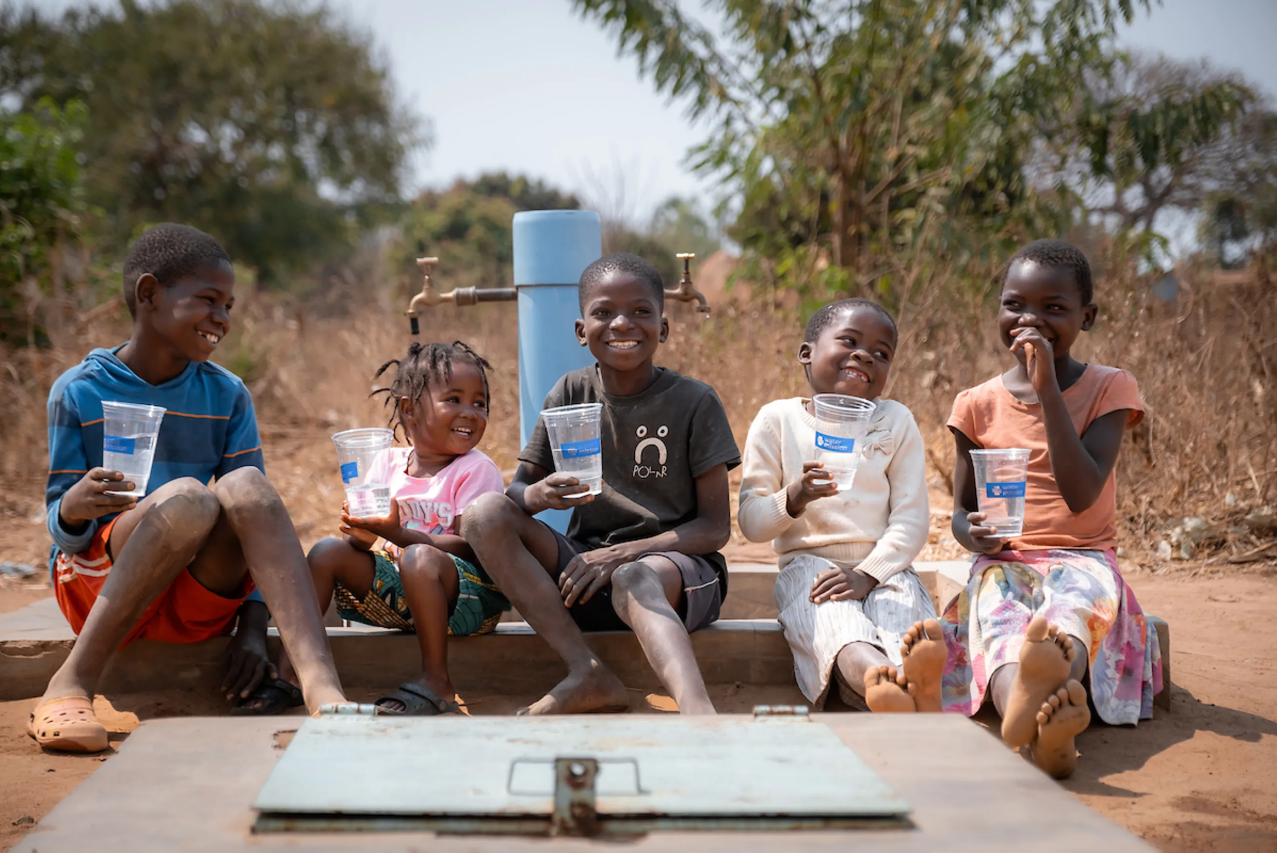 Children smiling in front of a tap stand
