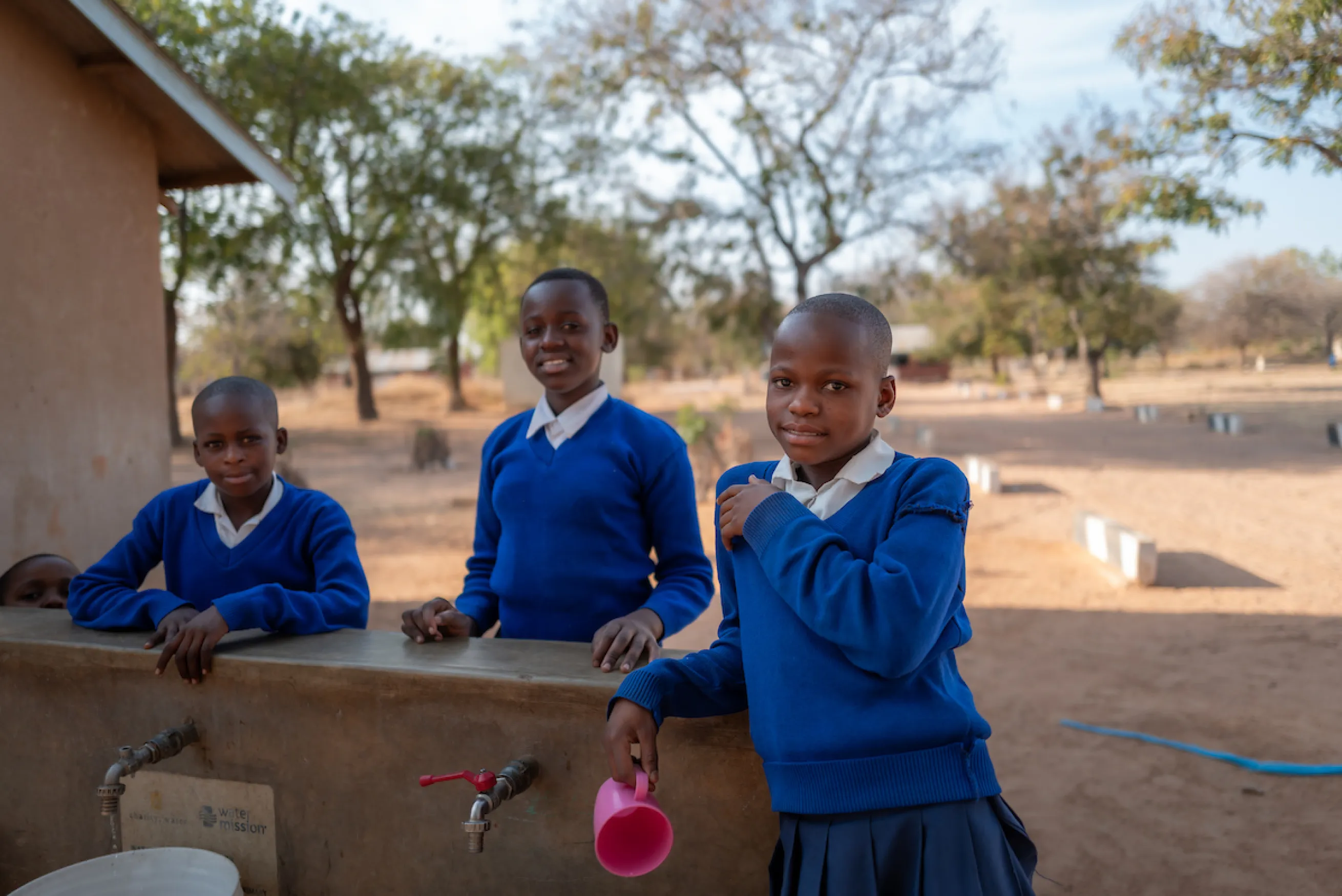 Three Tanzanian girls a the safe water access point in Mzogole, Tanzania