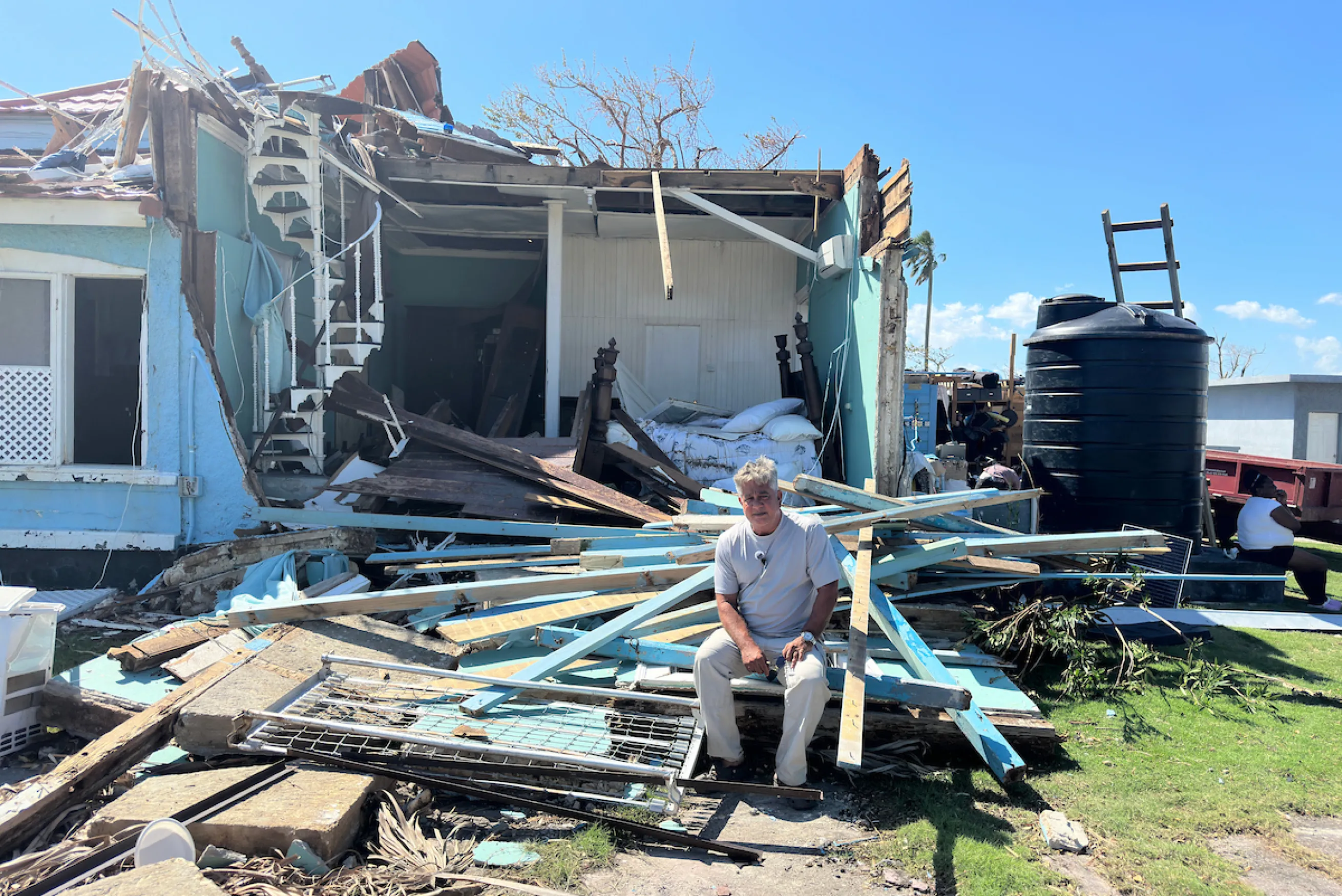 Jamaican man sits in front of his damaged home from Hurricane Melissa
