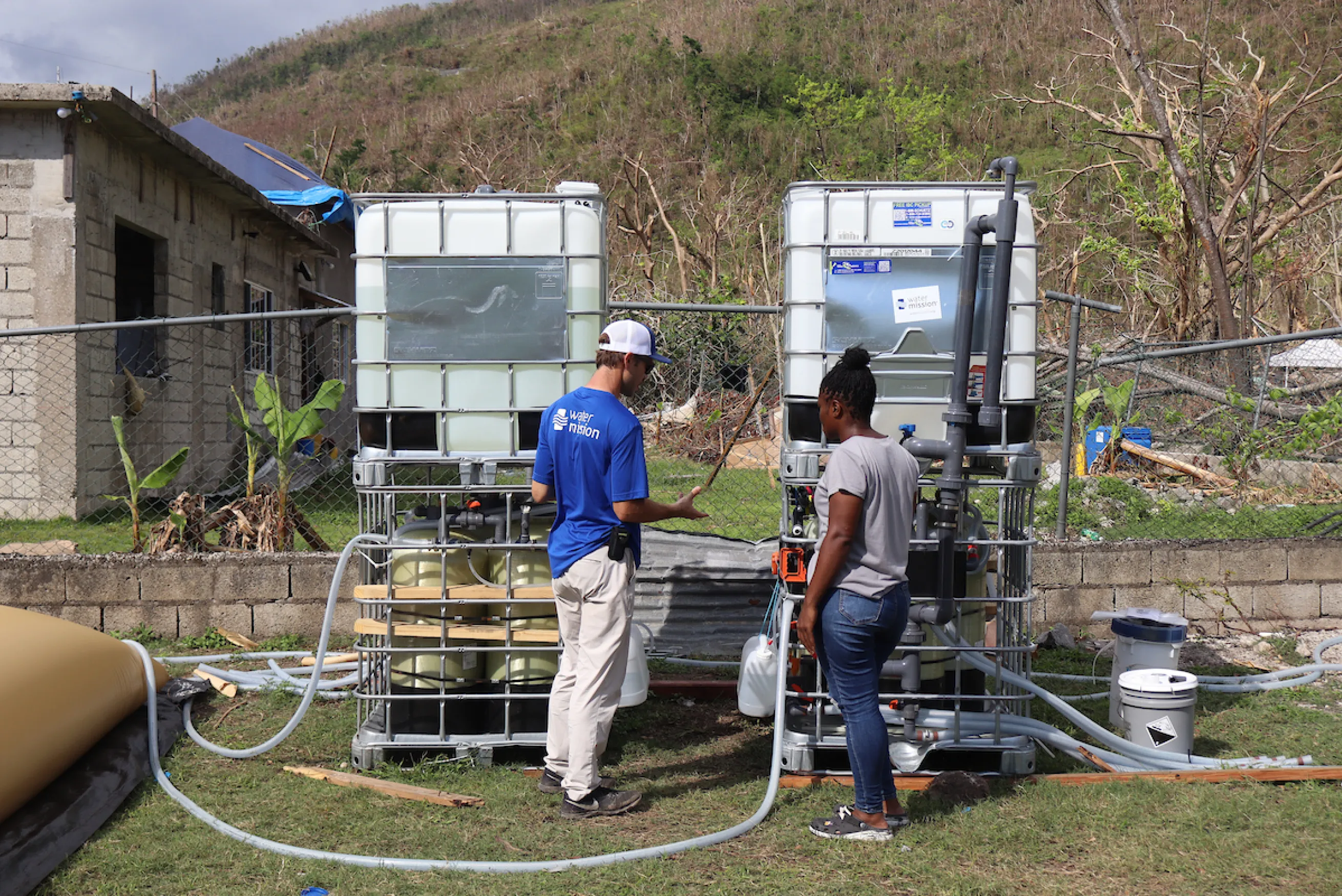 A Water Mission DART member teaches a Jamaican resident about thesafe water system