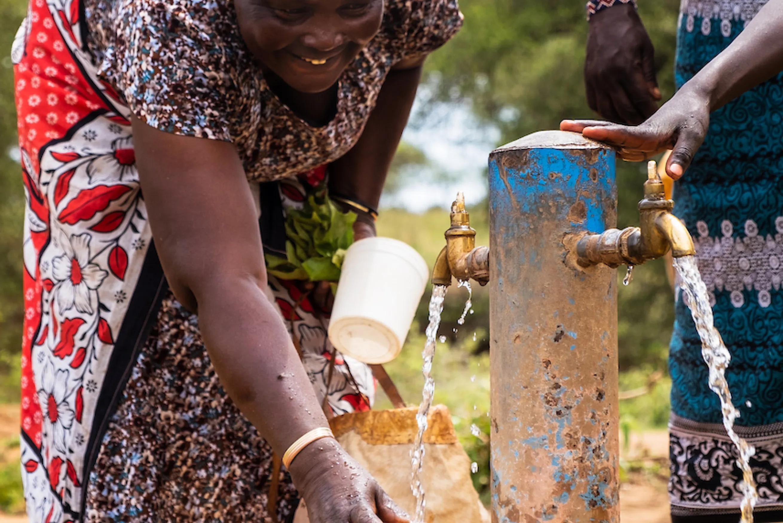 African woman collects clean water from a tap.