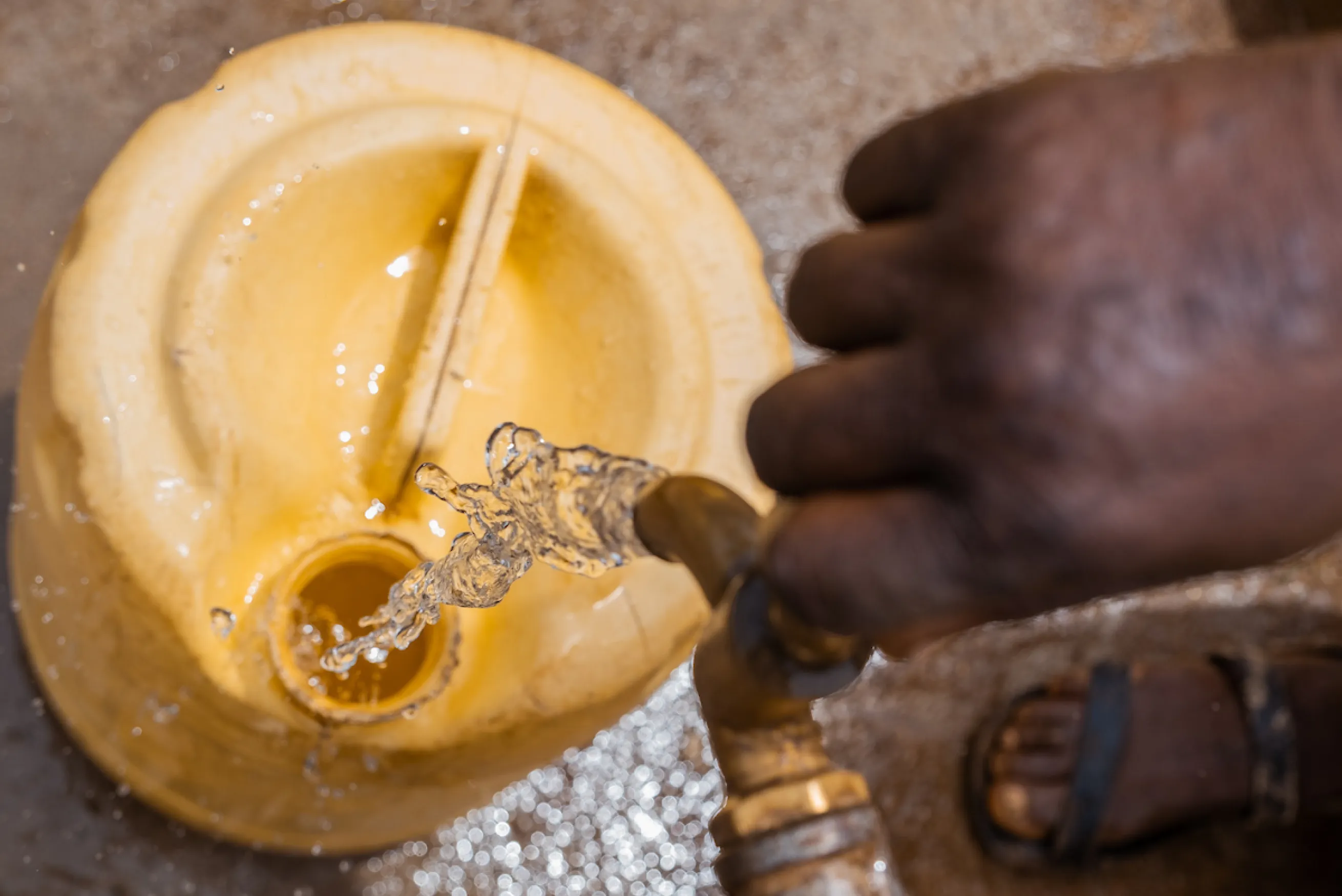 Clean water pouring from a tap into a yellow jerrycan