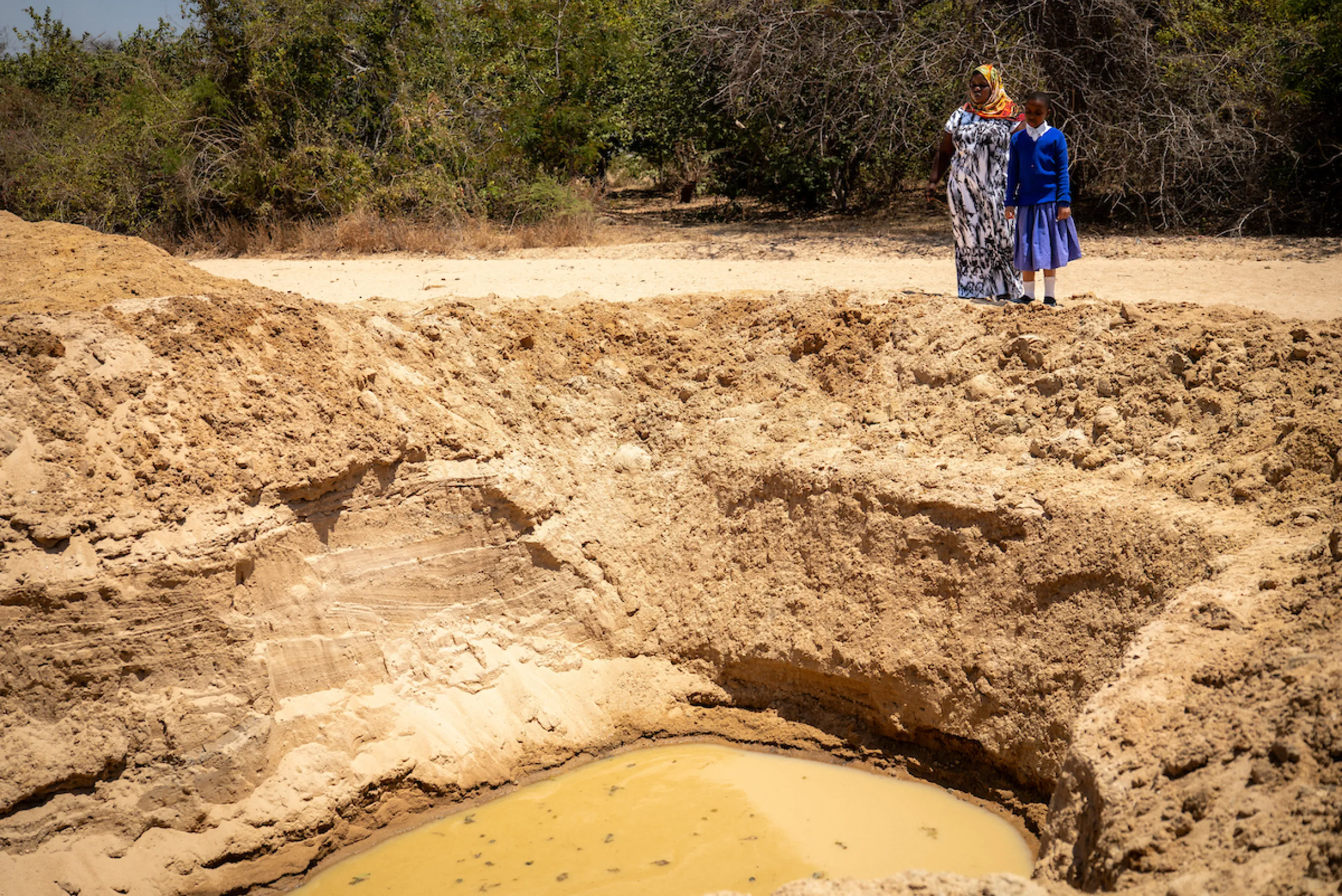 Pendo and her daughter beside their dirty water source