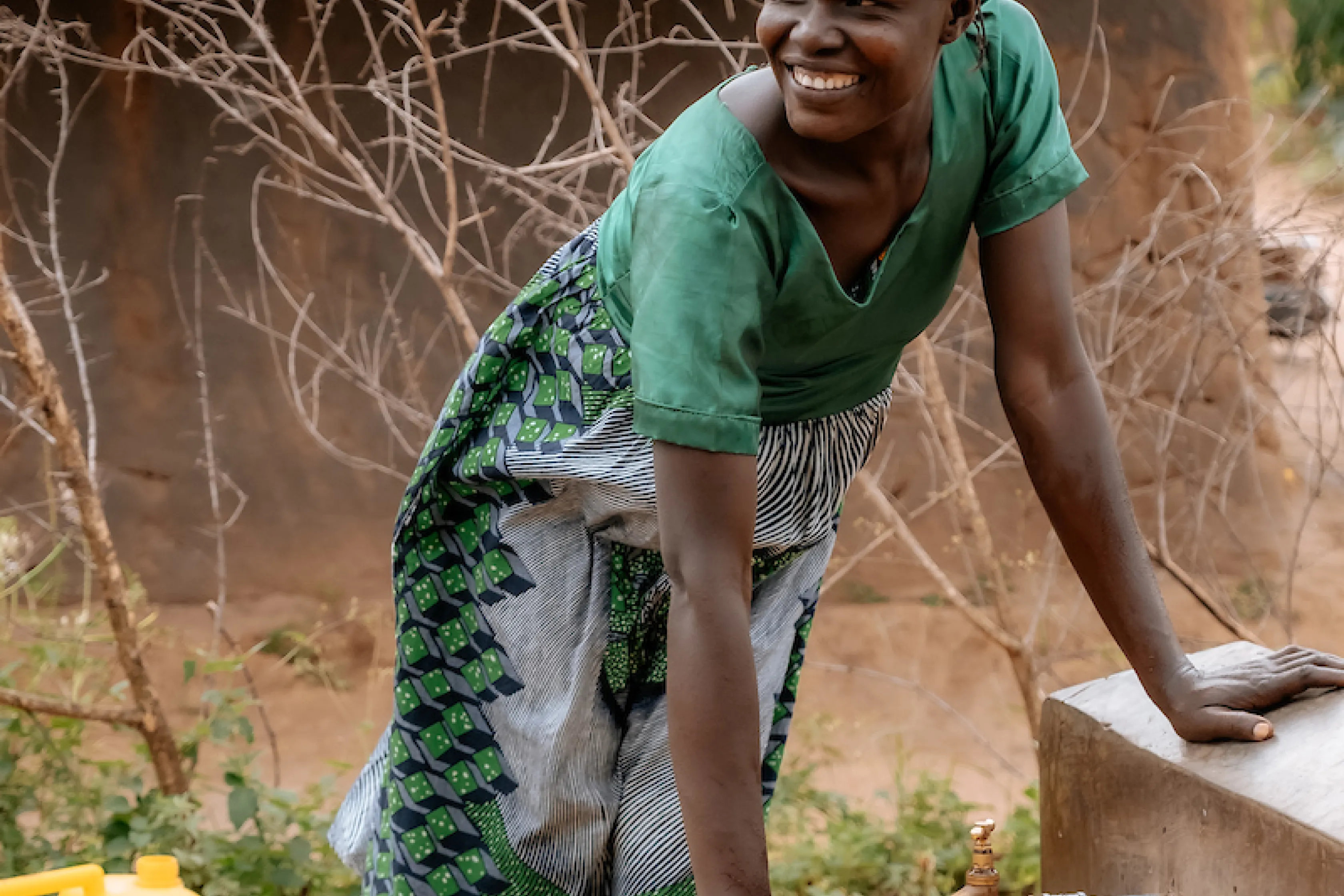 Edina smiles as she fills up jerry can with water