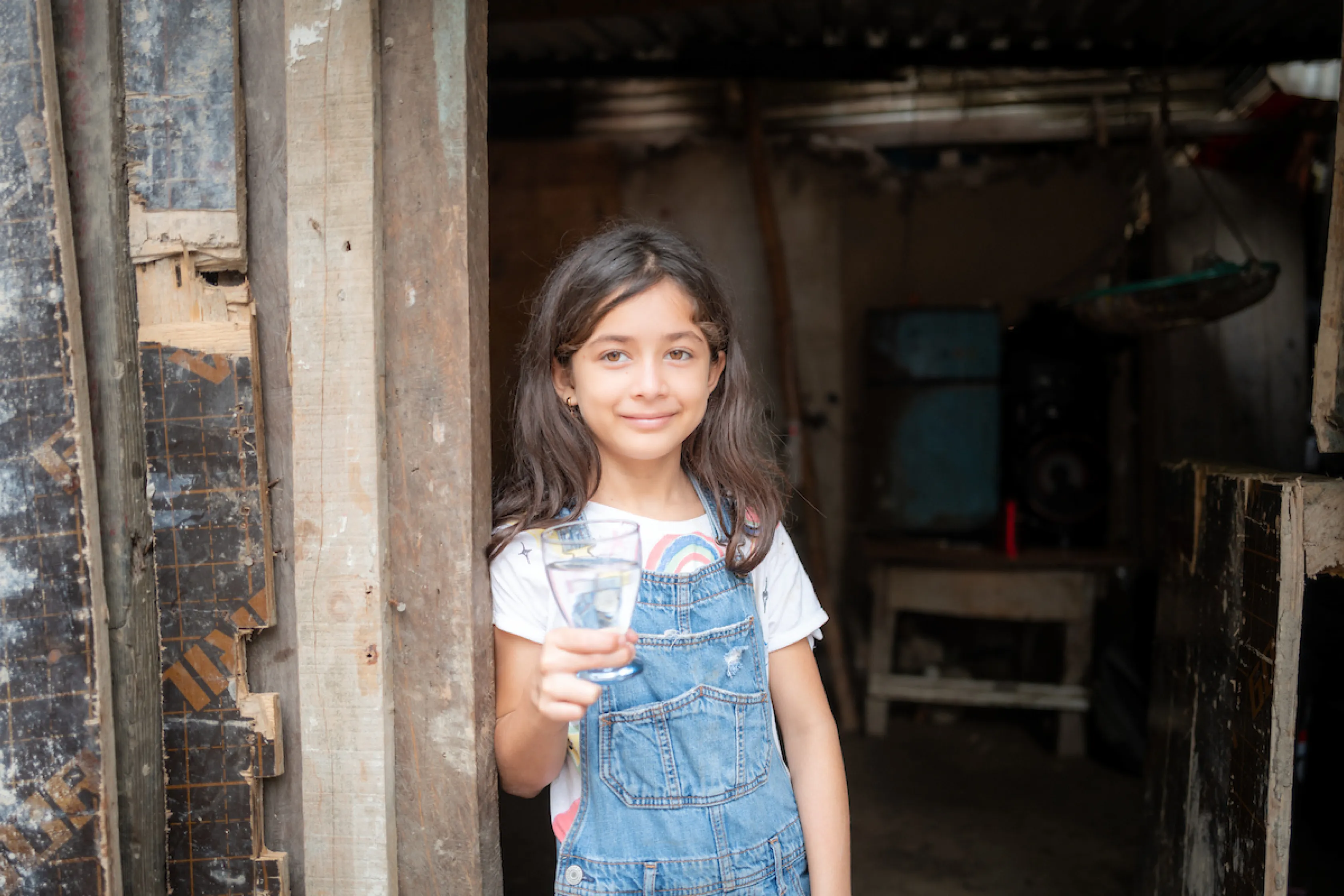 Little girl holds glass of water and smiles