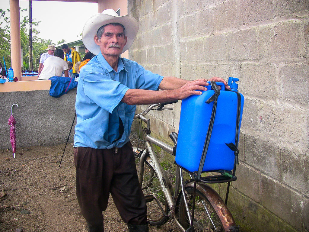 Honduras man carrying water on back of his bike