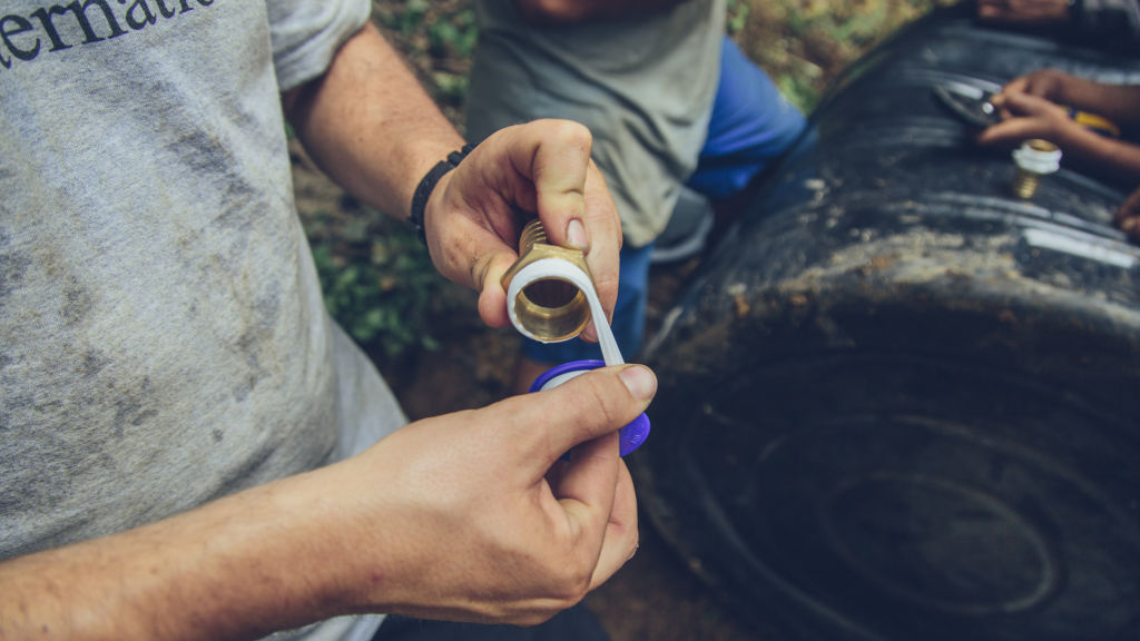 Tim Darms applies plumbing tape while installing a top tank for the system | Nepal Earthquake