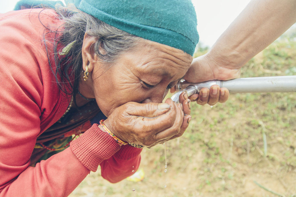 Nepali woman drinks safe water out of tap stand | Water Missions in Nepal