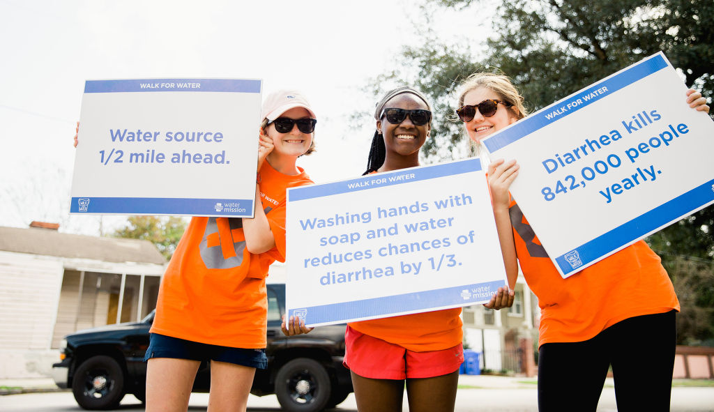 Volunteers hold up water crisis signs at the Walk for Water