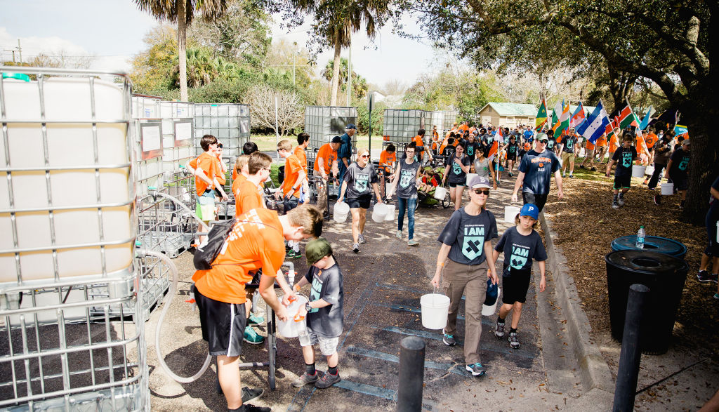 Walkers fill up buckets with dirty water in Hampton Park, Charleston, SC.