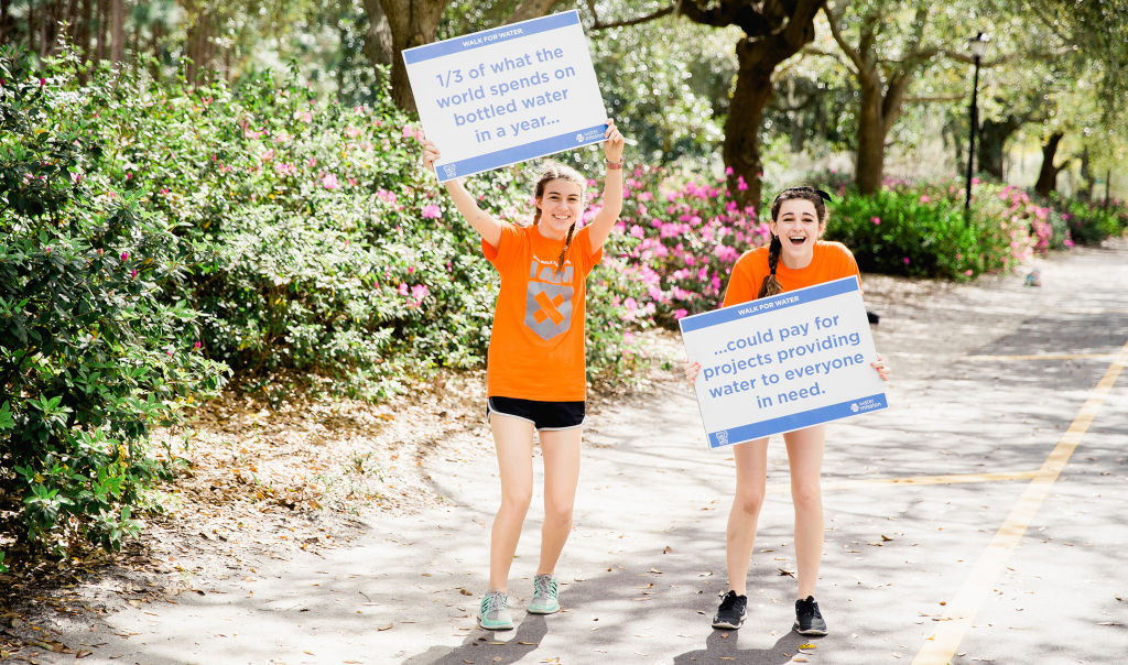 Volunteers hold up signs about the global water crisis.