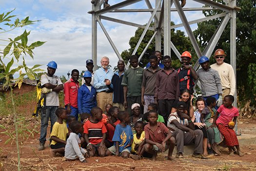 The Project Elev8 team stands in front of the safe water tower with the community.