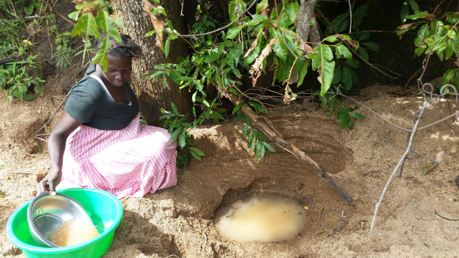 A South Sudanese mother collects dirty water for her family in a Ugandan refugee camp.