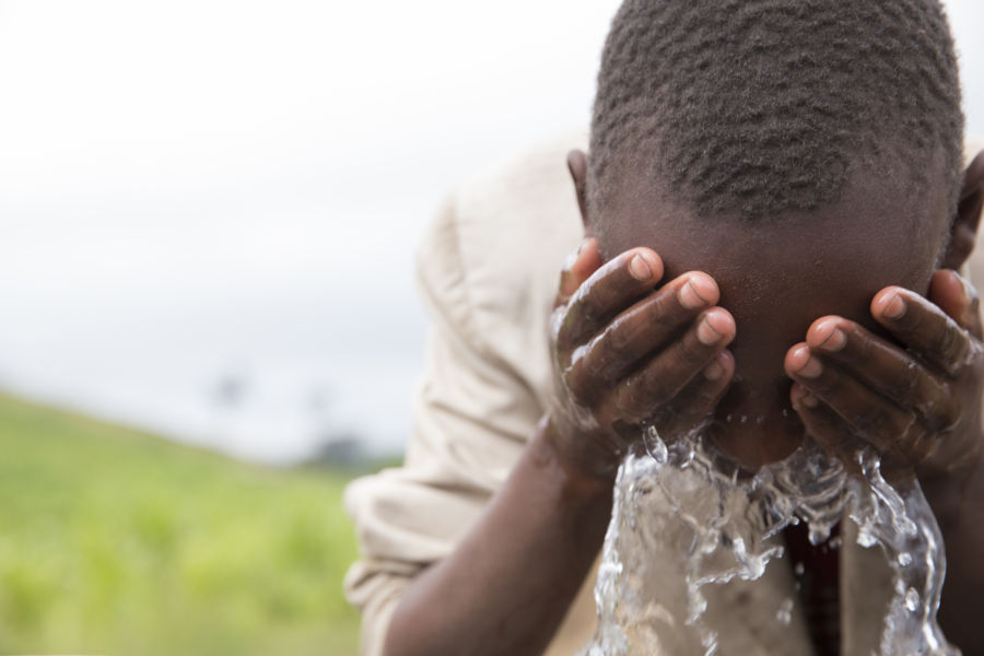 Young boy in Enariboo, Kenya, washes his face with clean, safe water for the first time.