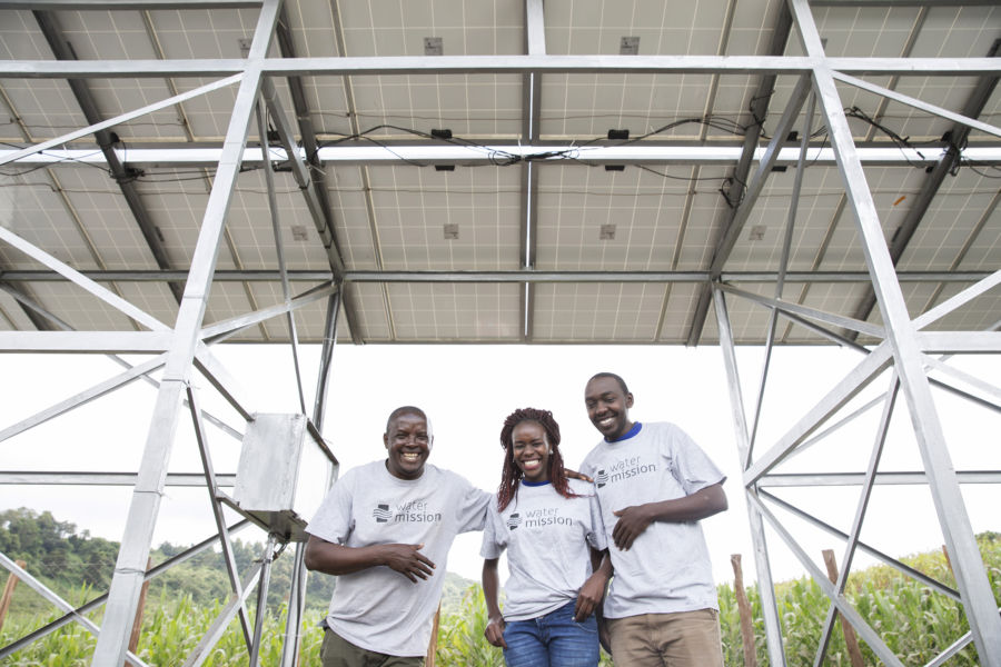 Water Mission staff stand under the solar rack in Enariboo, Kenya.