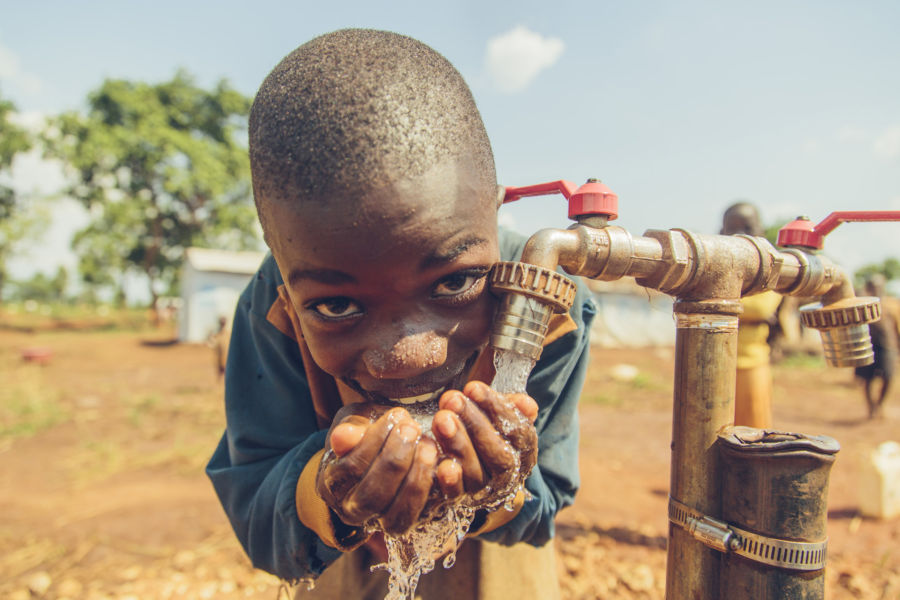 Young boy drinks safe water from a tap in Nyarugusu Refugee Camp, Tanzania.