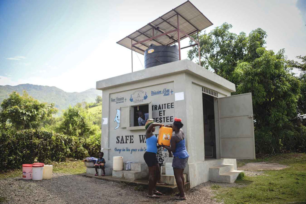Women collect safe water from a solar-powered water project in Haiti.