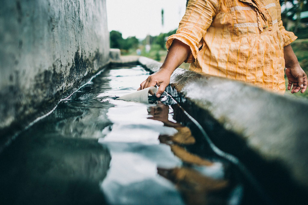 A woman in Indonesia collects dirty water to wash dishes.